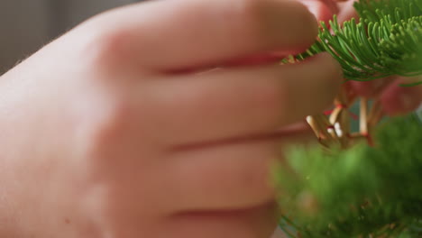 close hand view fixing handmade straw ornament on christmas tree, capturing delicate festive moment, cozy atmosphere, celebrating holiday tradition with natural materials