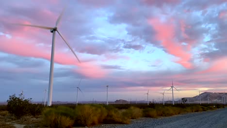lapso de tiempo de la granja de turbinas eólicas de energía alternativa contra el espectacular cielo rosado de la puesta del sol