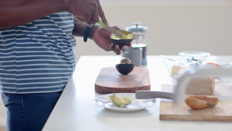 african american man chopping avocado in sunny kitchen, slow motion