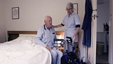 elderly care in bedroom with nurse assisting senior man with walker