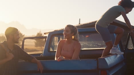 Gruppe-Von-Freunden-Entlädt-Rucksäcke-Vom-Pick-up-Truck-Auf-Dem-Roadtrip-Zu-Einer-Hütte-Auf-Dem-Land