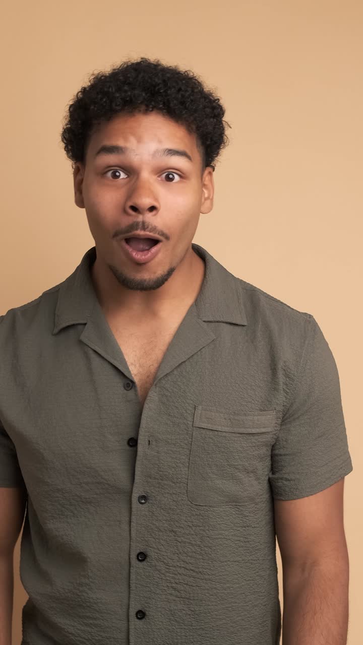 Surprise young man smiling at camera in beige studio