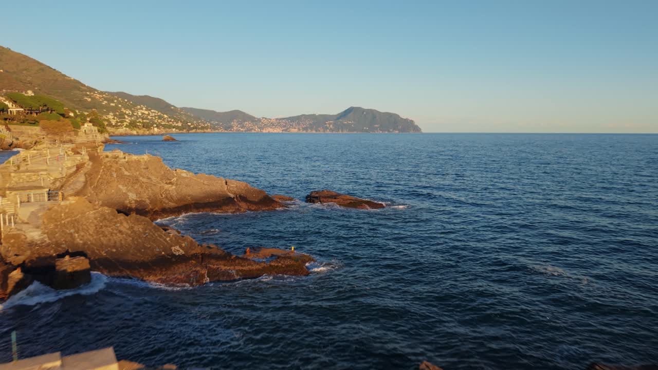 Rocks and the mediterranean coastline with a sunset glow in genoa, italy, aerial view