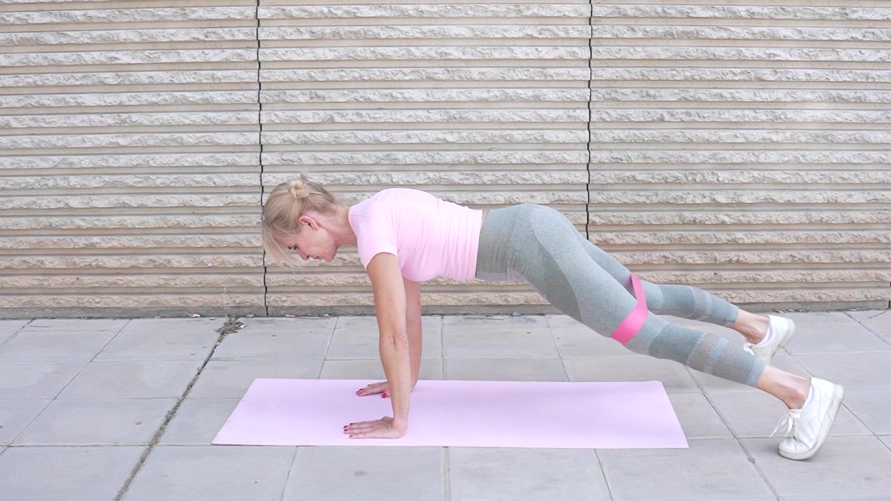 Woman is doing a plank exercise outdoors as a part of her fitness training routine