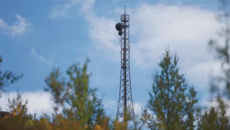 a communication tower with antennae stands above the autumn forest