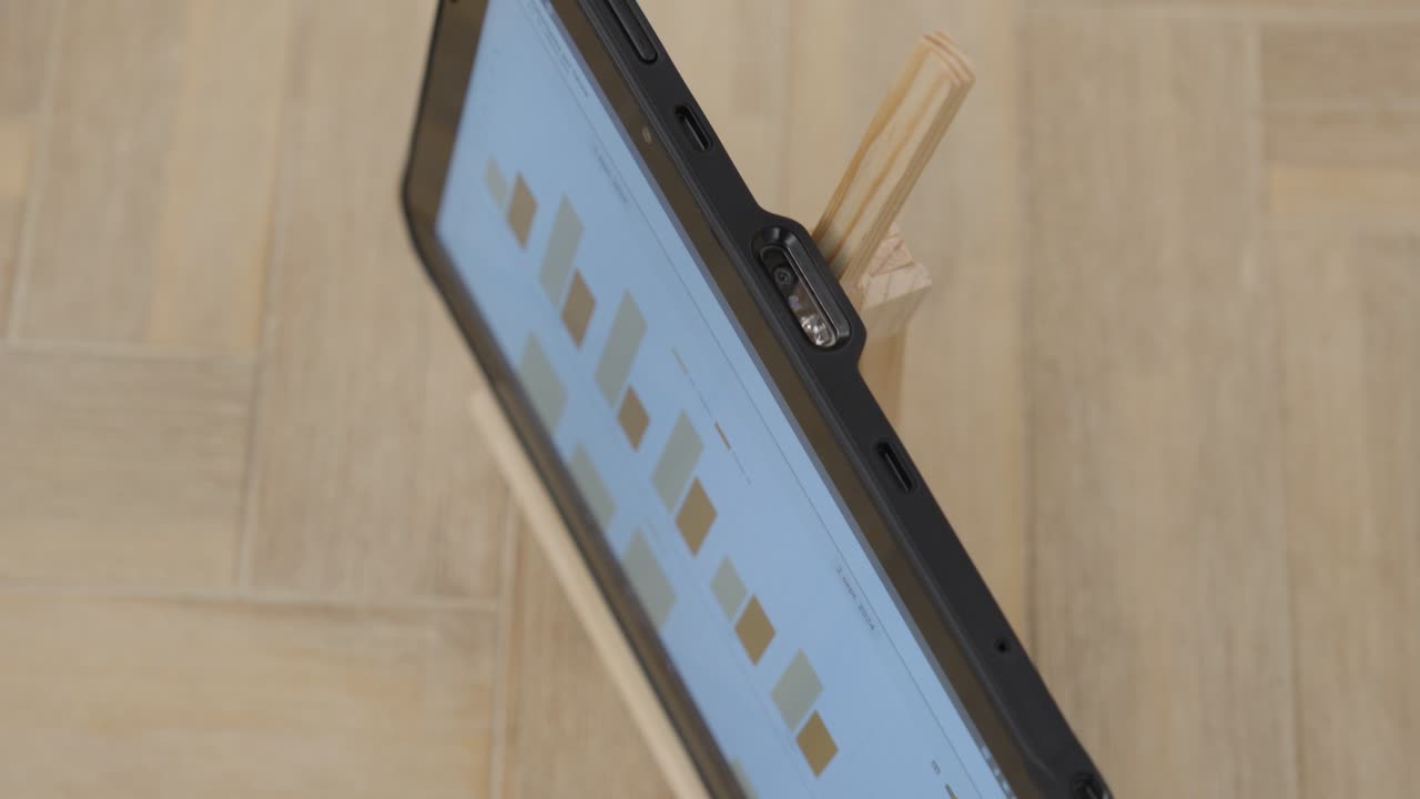 angled tablet on wooden stand displaying data blocks in orange tones on light screen interface