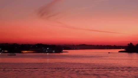 el cielo del atardecer naranja dorado se refleja en el lago tropical, los barcos desnatan la superficie