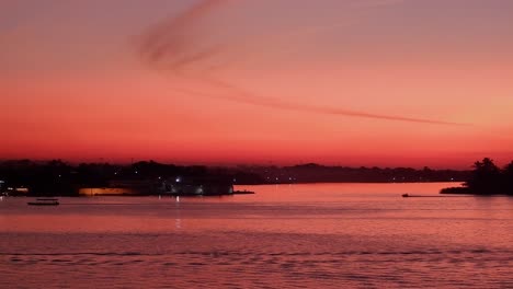 golden orange sunset sky reflects in tropical lake, boats skim surface