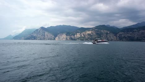 video of a river ferry sailing from left to right on lake garda, italy with the surroundings hills and views.