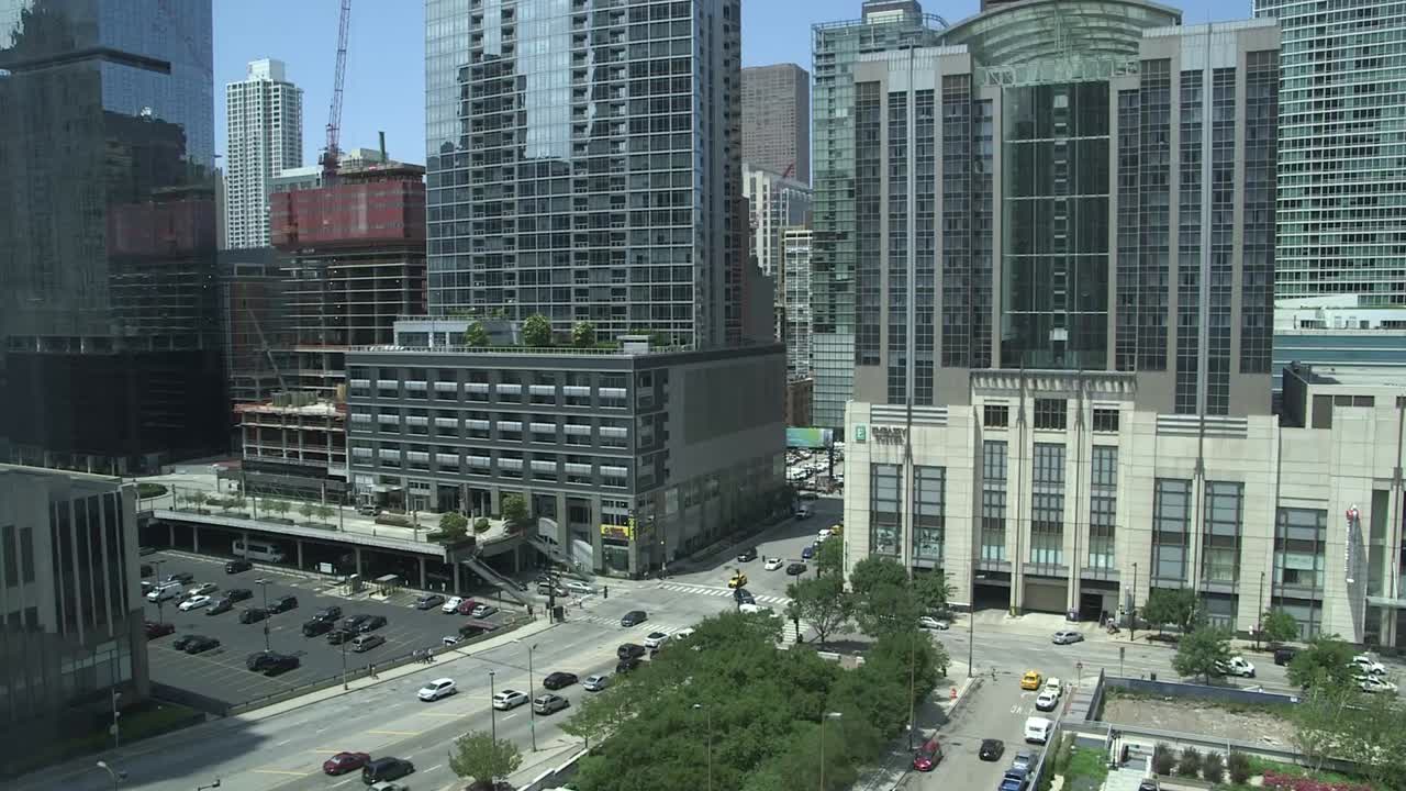 Chicago downtown streets and modern high-rise buildings near Aon Center, with traffic and construction cranes, daytime urban cityscape in the Loop