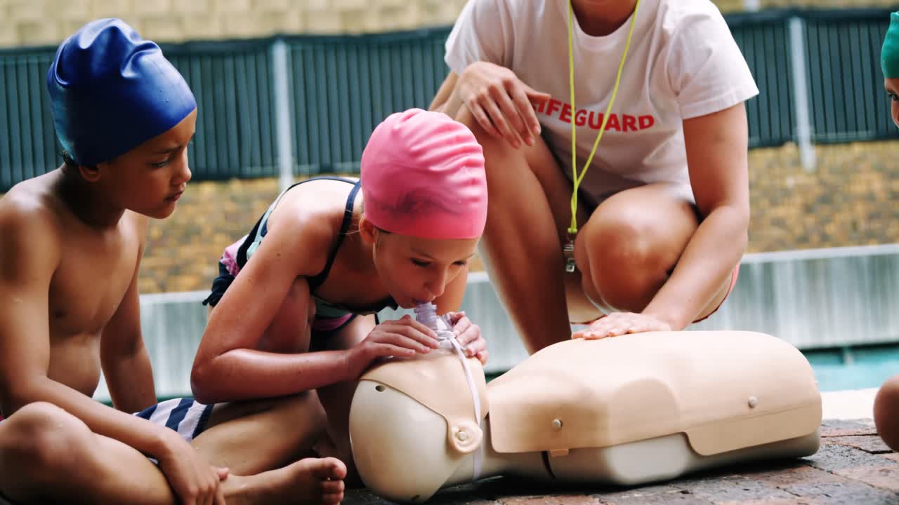 수영 코치가 인형 위에서 학생들을 훈련시키고 있습니다.