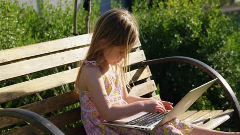 chica usando computadora portátil en el jardín 4k