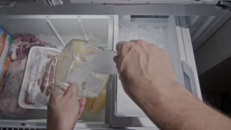 a man collects ice from the icemaker of a domestic refrigerator