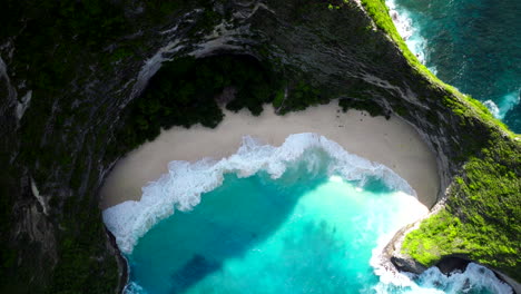 drone top down rising above kelingking sandy cove with turquoise blue water bali