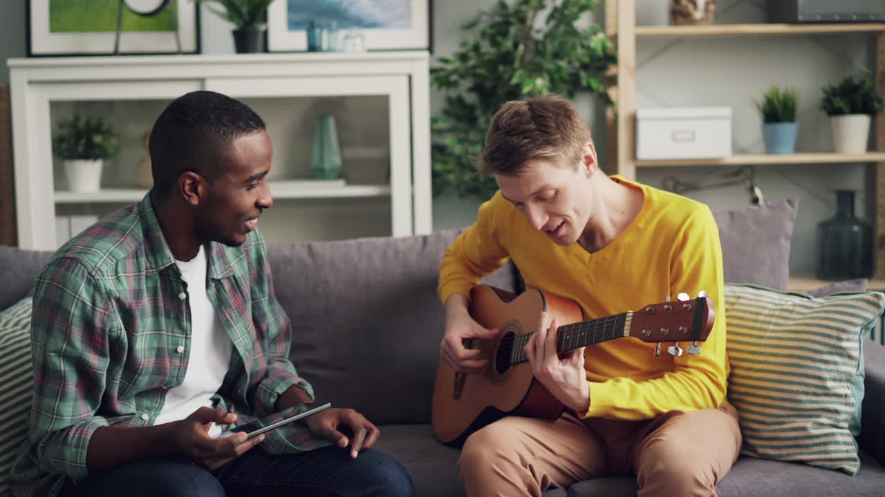 Two friends playing guitar in living room