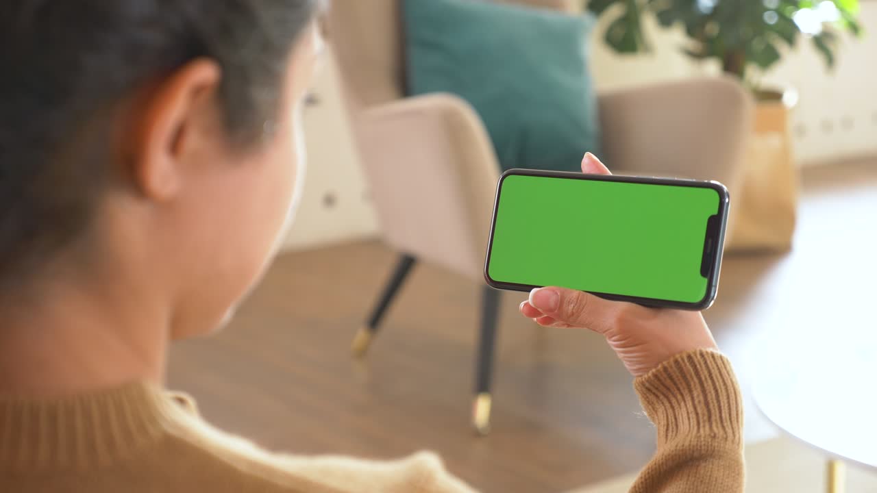 젊은 여성의 손은 수평 녹색 화면 인터넷 기술로 전화를 들고 만지고 있습니다.