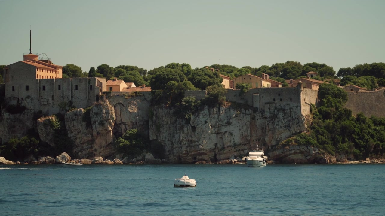 Edifici della fortezza Fort Royal arroccati su scogliere dell'isola di Santa Margherita, arcipelago delle Lérins, circondati da alberi verdi e dal mare Mediterraneo blu.