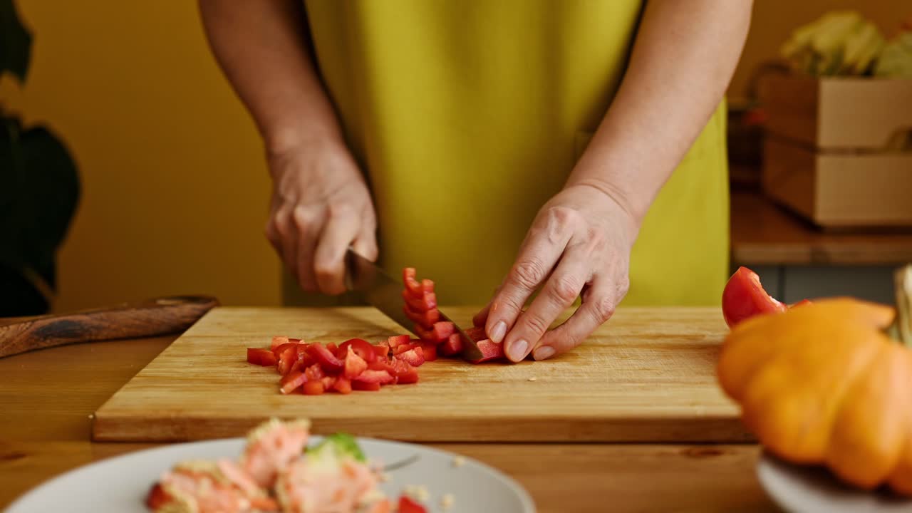 анонимная женщина режет красный перец на доске для резки.