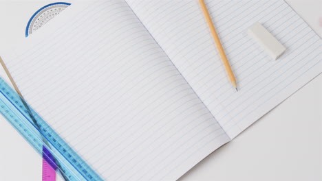 close up of open notebook with school stationery on grey background, in slow motion