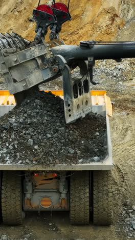 heavy excavator loading rocks into a dump truck at a mine site