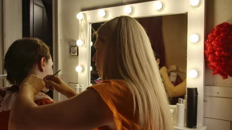 makeup artist applying clown makeup for a halloween event