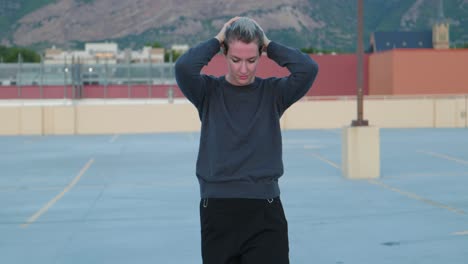 caucasian white lady women girl in empty parking lot with hands on head as she has mental illness breakdown with mountains and building in background