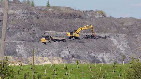 shot of an excavator dumping rubble into the back of a rock hauler dumper truck at a open cast mine