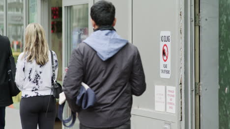 People-wait-in-line-at-a-distance-for-a-store-entrance