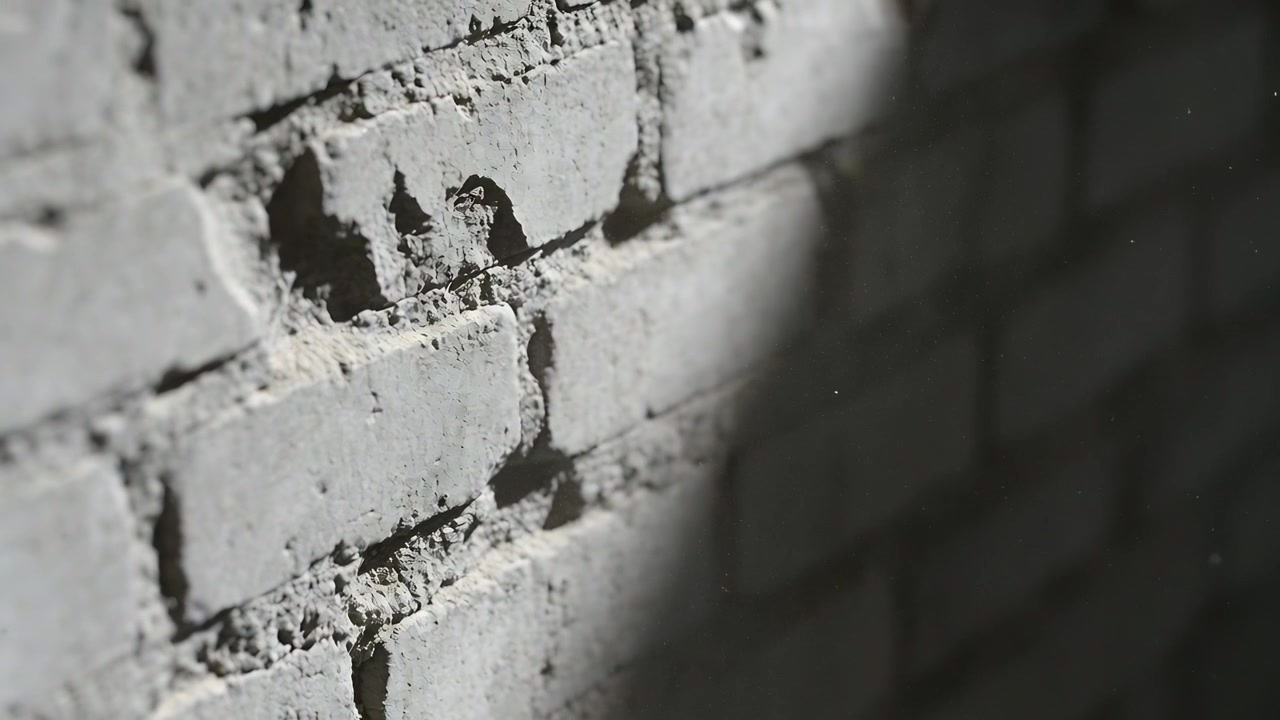 Shifting light causing camera racking in hall, painted brick wall showing chipped mortar and dust