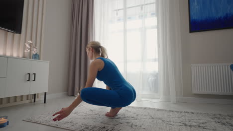 a young woman in isolation does yoga at home on a mat in her apartment