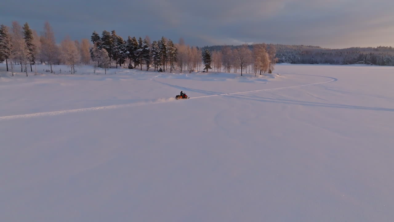 Aerial view around a snowmobile driving on ice, arctic sunset in the Nordics