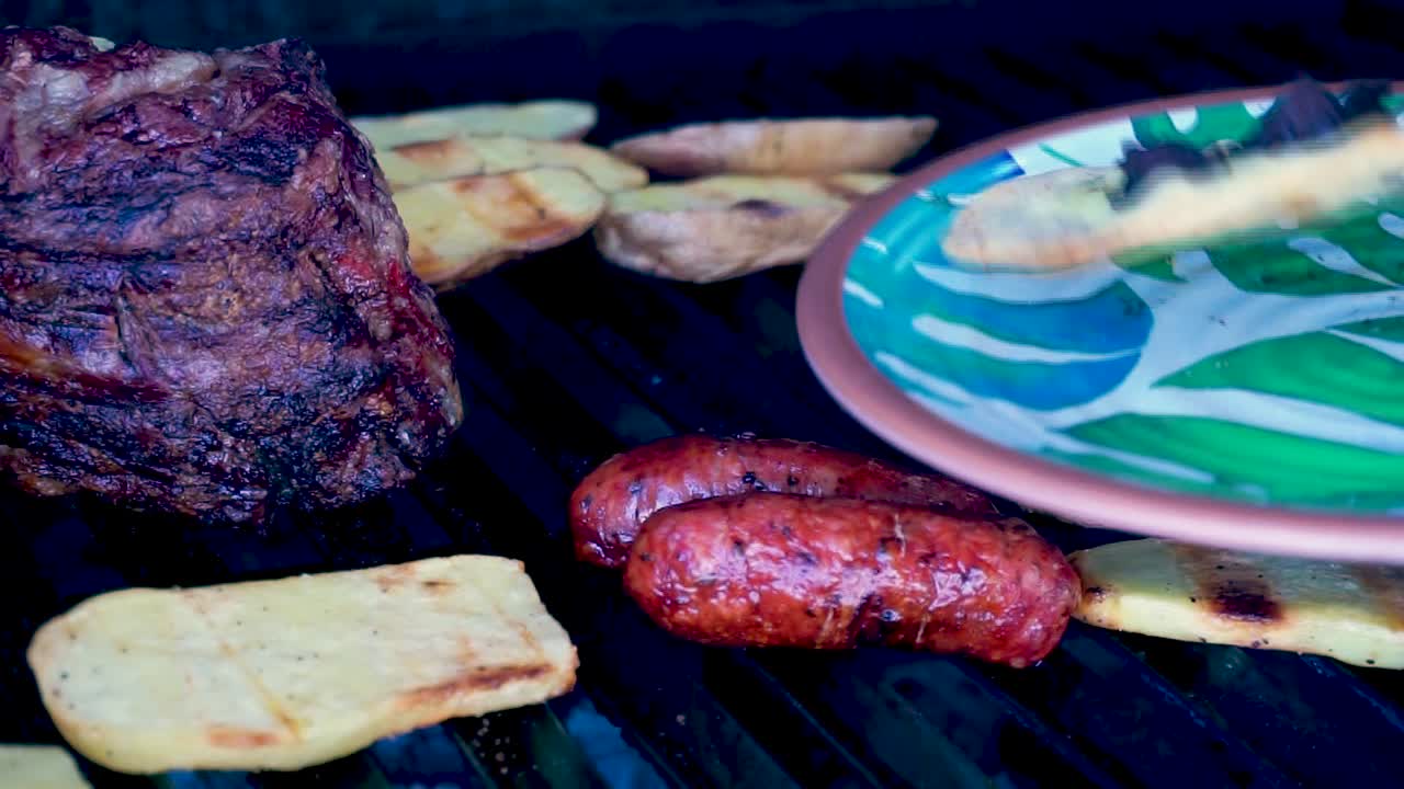 en primer plano, carne a la parrilla con chorizos, tortillas de queso, frijoles guatemaltecos y patatas asadas fumando y preparación jugosa lista para comer en familia en un día de la temporada de verano [hd1920 x 1080] fps 29
