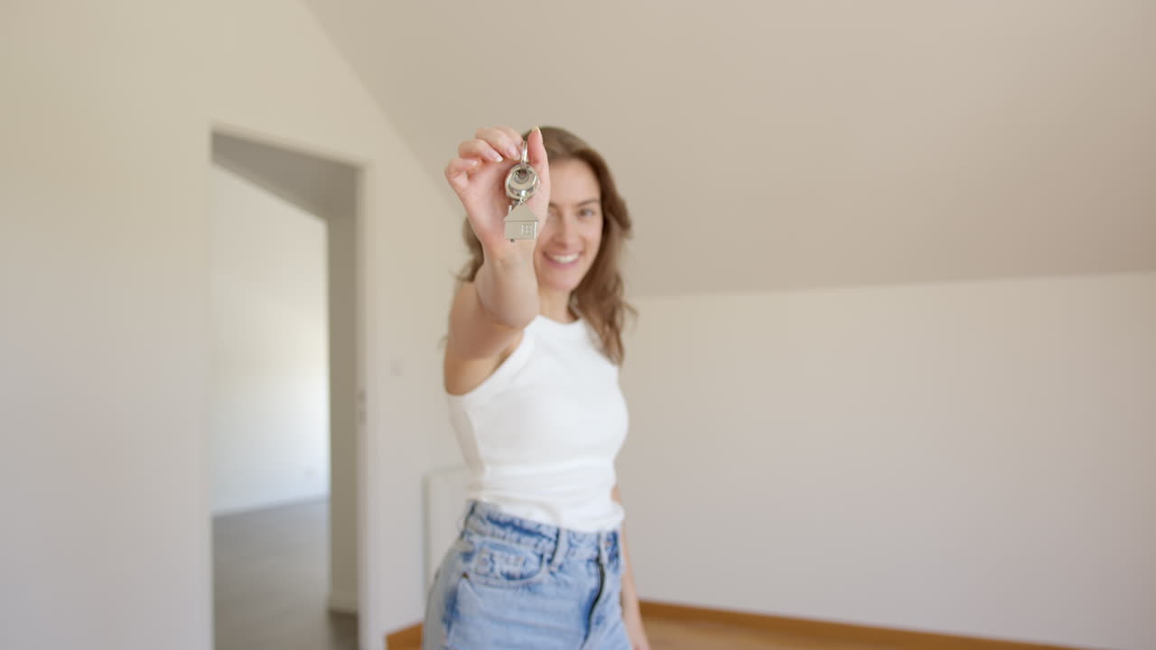 Happy woman entering her new home, showing keys of purchased property. Pan right