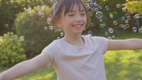 spinning girl outdoors having fun playing with bubbles in garden