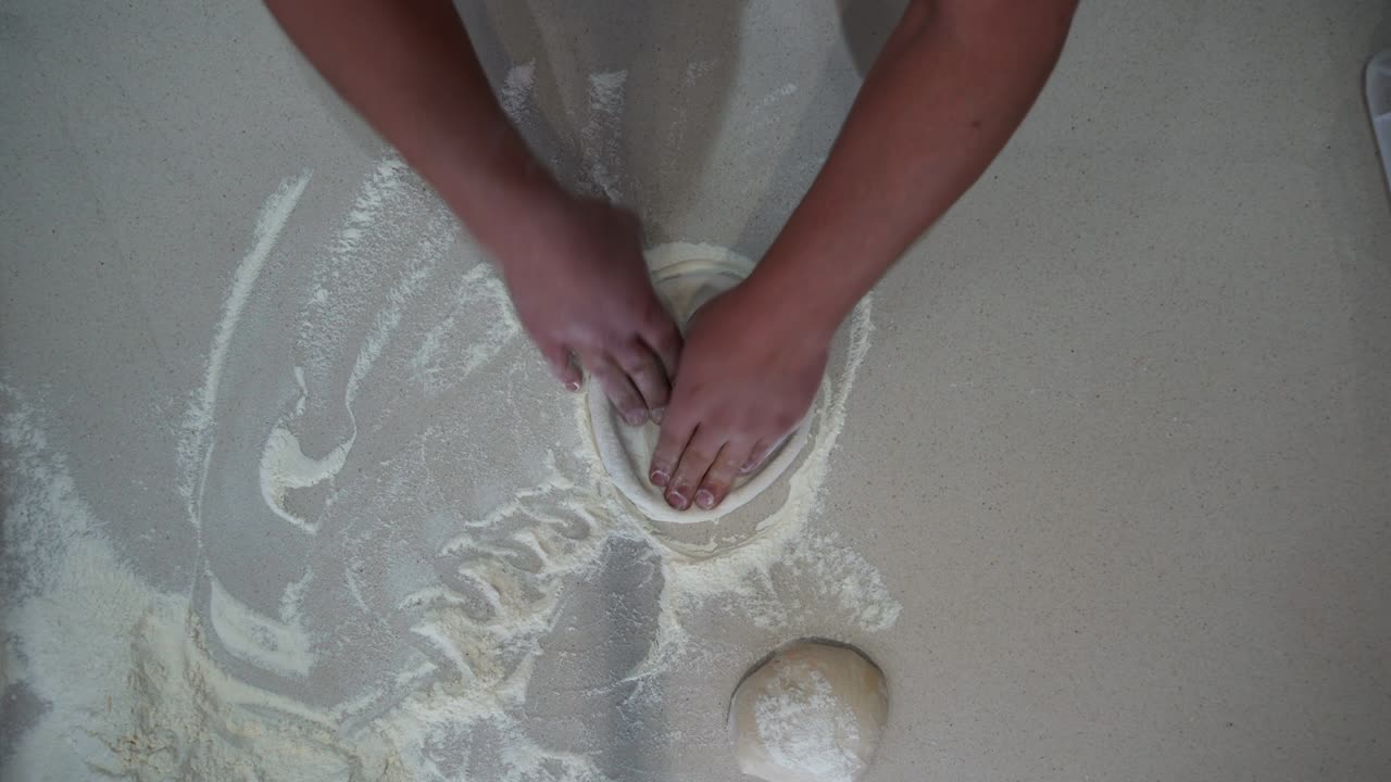 Overhead view of professional cook making pizza dough on the table. Top down view of a chef flattening dough balls into circular pizza dough