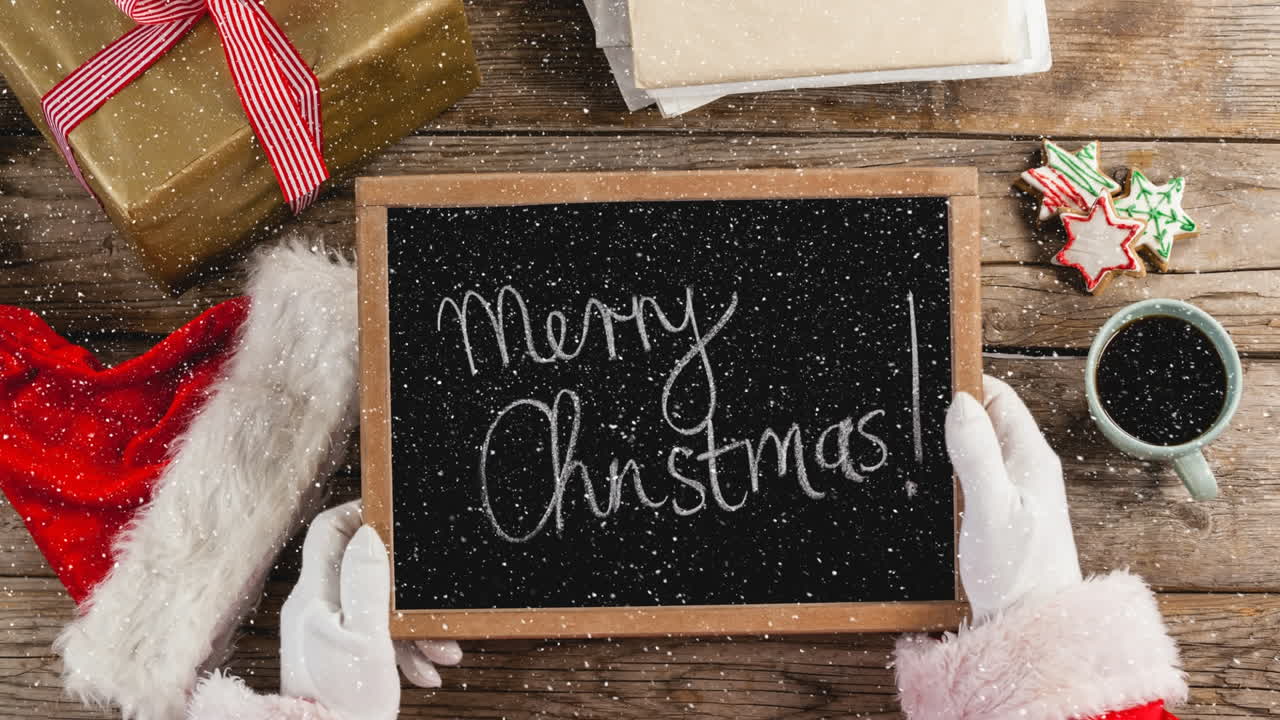 composición de video con nieve sobre el escritorio con santa sosteniendo la tabla negra