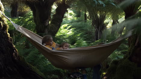 children relaxing and playing in a hammock in a lush forest