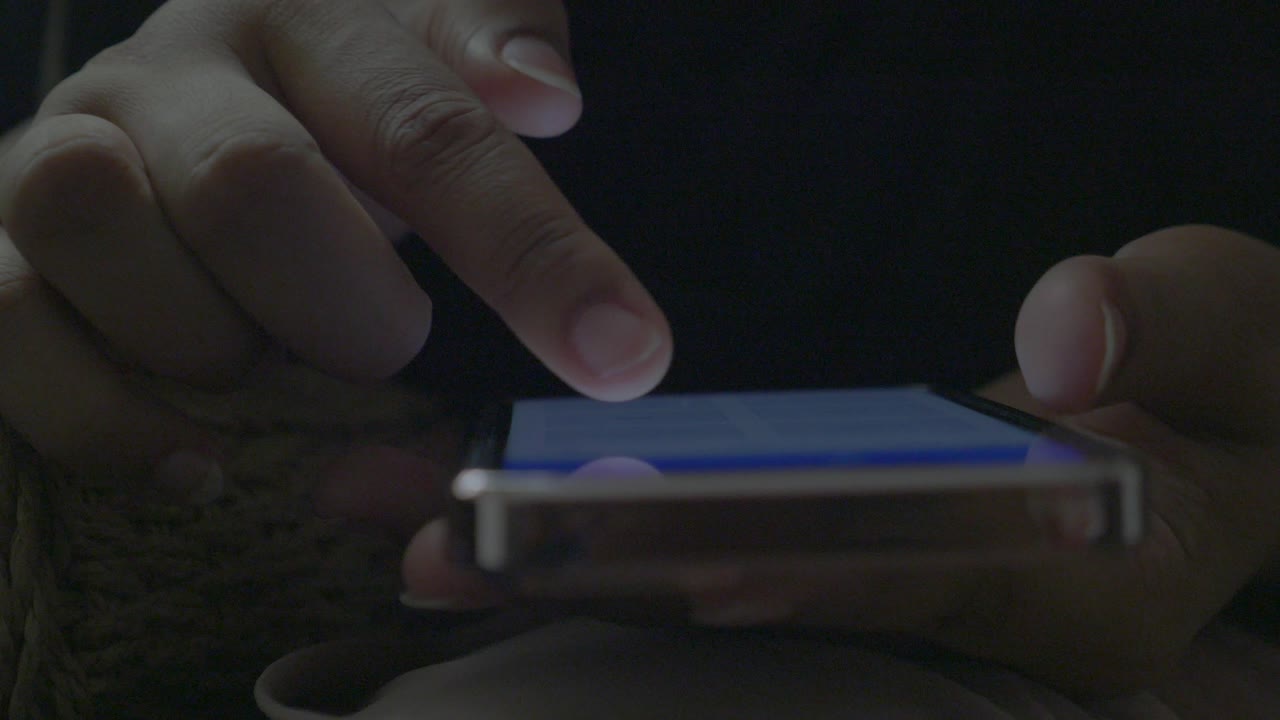 persona que utiliza un teléfono inteligente por la noche
