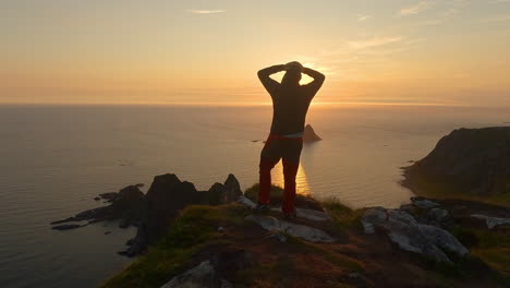 Men-looking-into-the-sunset-at-the-ocean-and-island-Bleiksoya-rock-landscape-in-Norway