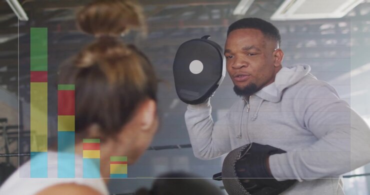 Cueing trainer holding black mitts guiding gloved boxer in white tank drilling in ring, bar-chart