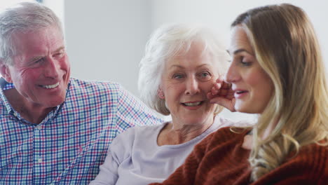 Ältere-Eltern-Mit-Erwachsener-Tochter-Sitzen-Zu-Hause-Auf-Dem-Sofa-Und-Reden-Und-Lachen