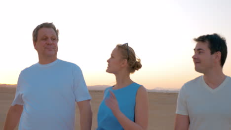 three people enjoying evening walk on the beach