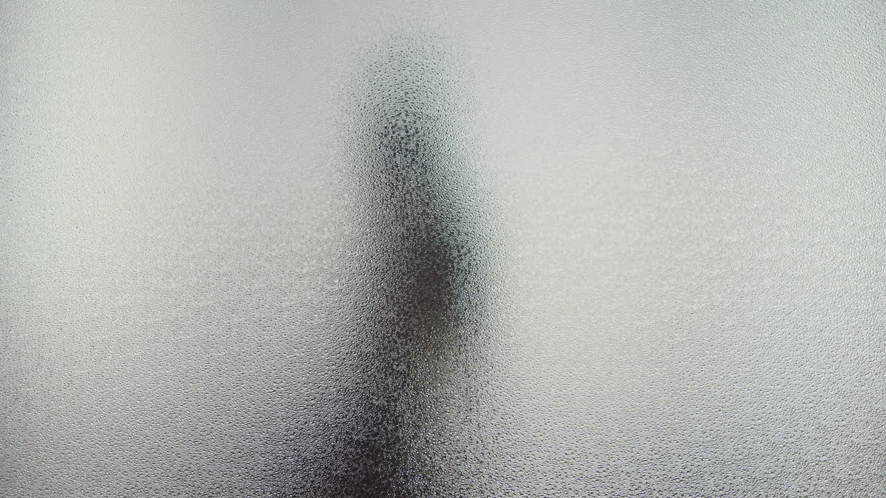 A female silhouette behind the frosted window dances slowly