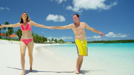 caucasian couple in swimwear walking on caribbean beach