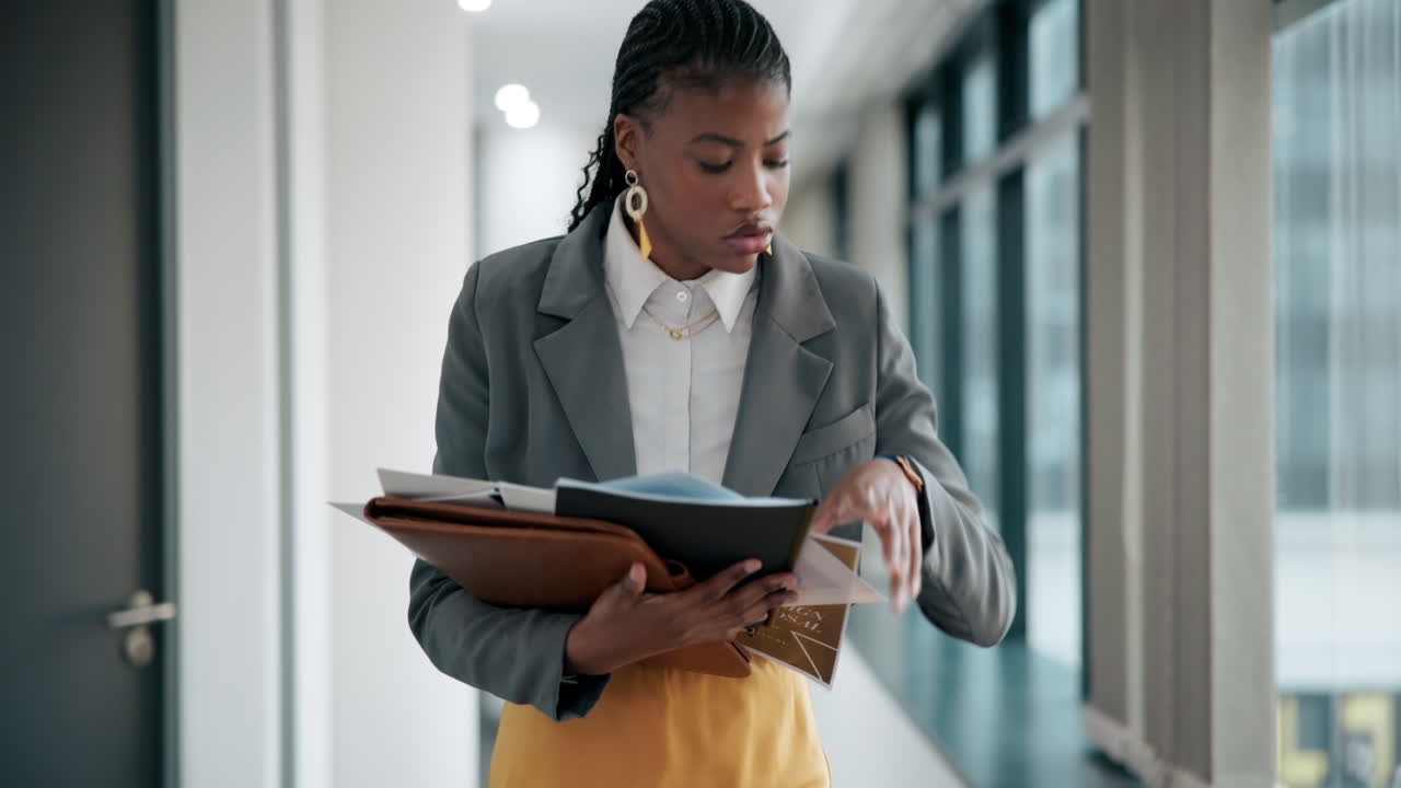 Businesswoman reviewing documents in office hallway