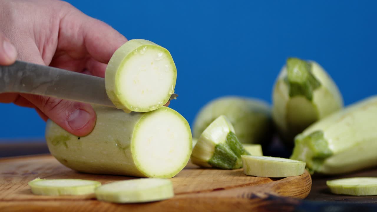 칼로 은 수키니 조각을 절단판에 은 남자 손.