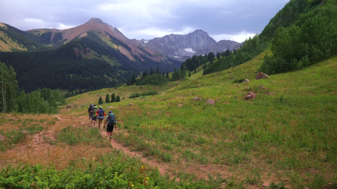 Group of friends backpacking camping hiker hiking trail landscape view of Capitol Peak 14er wilderness trailhead Colorado cloudy afternoon grey skies summer Rocky Mountains Elk Range Aspen Trees