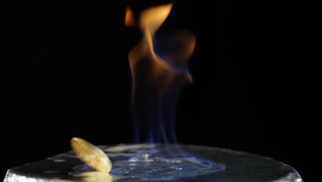 bitcoin coin spins dangerously close to a burning flame on a reflective surface, symbolizing risk, crash, and volatility