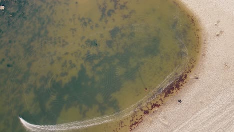 Overhead-Shot-Of-Person-Playing-With-Fast-RC-Boat-On-Ericeira-Sandy-Beach,-Portugal