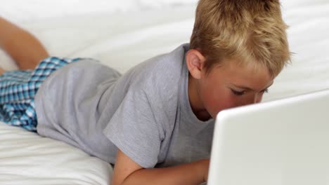 Little-boy-using-laptop-on-bed